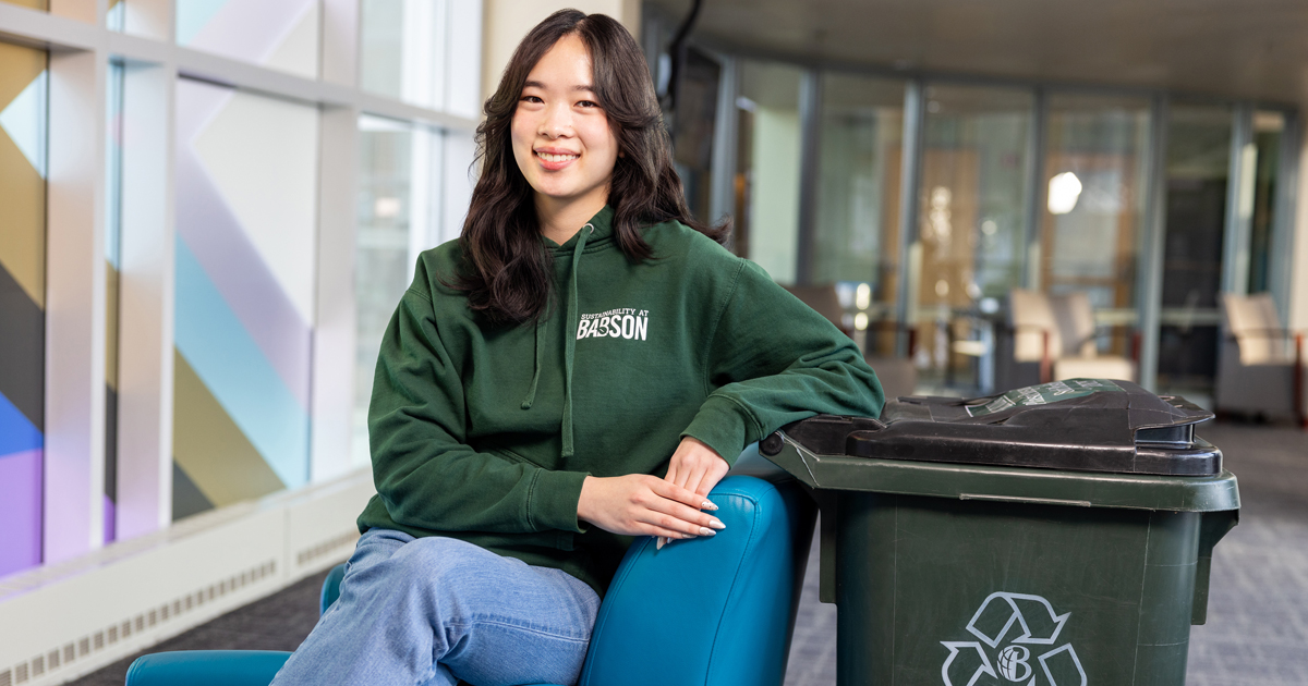Natalie Chong poses for a photo while leaning on a recycling bin